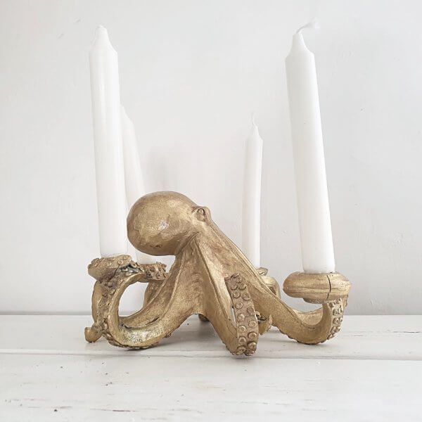 Side view of gold octopus candlestick with white candles